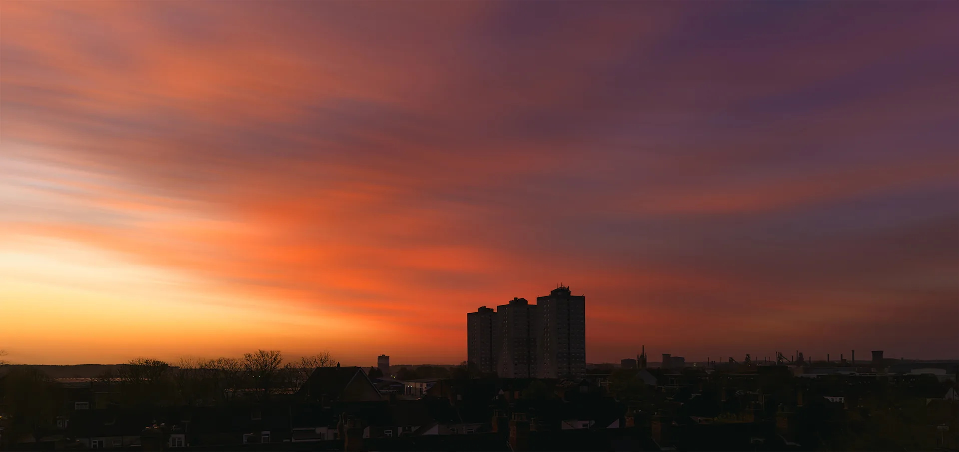 A red evening sky above a town, with a tall building silhouetted against the light