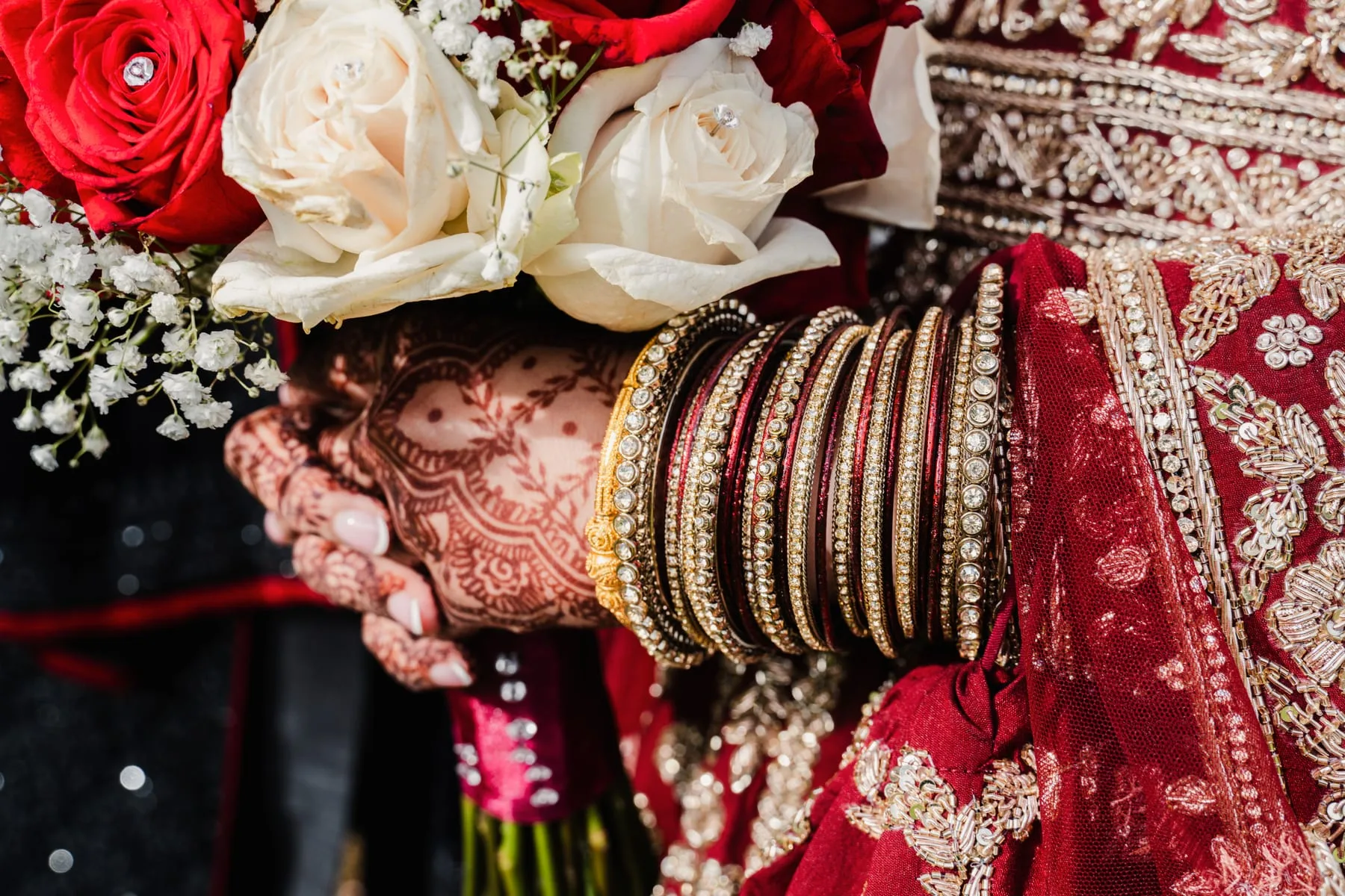 Bride's henna, bangles, bouquet and embroidered red wedding outfit