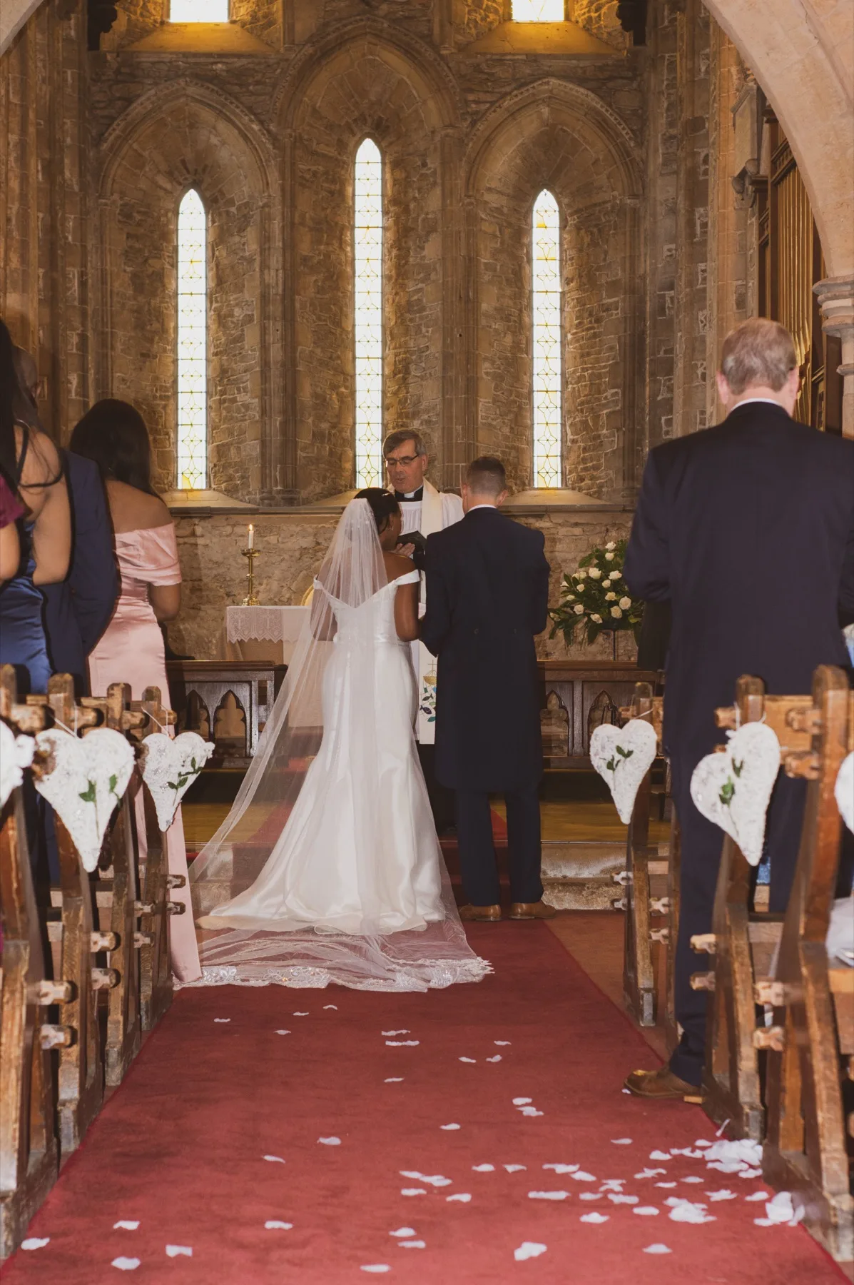 Wedding ceremony viewed along the aisle of a stone church